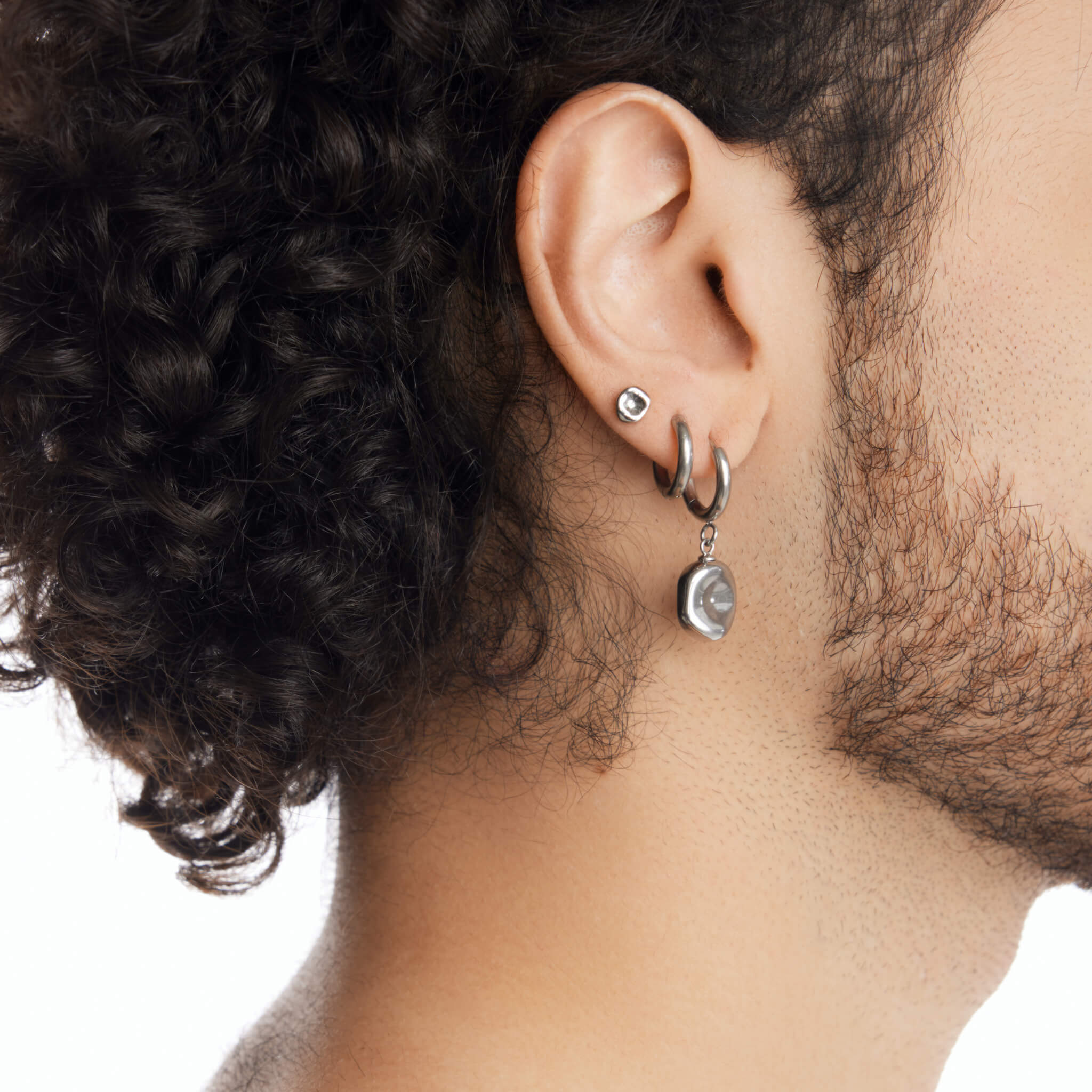 Dawn women's pendant earring by Five Jwlry, born from Alicia Moffet's collaboration. This design marries a timeless hoop with a pendant resembling a water droplet, creating an illusion of molten metal frozen in time. Available in 14k gold or silver, made from water-resistant 316L stainless steel. Hypoallergenic with a 2-year warranty.